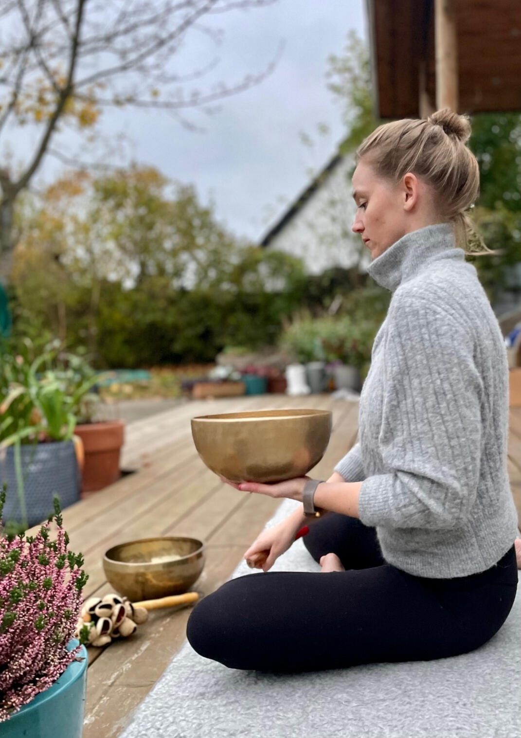 Hånd over handpan med klangskål og bløde tekstiler i baggrunden
